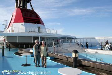 Couple standing on a cruise ship pool deck under blue sky