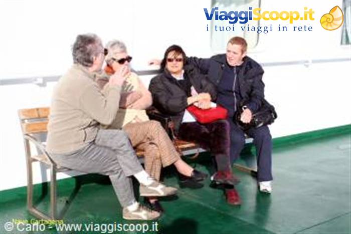 Four passengers sitting on a wooden bench on a ferry deck