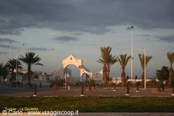 White arch and palm trees in a square at sunset