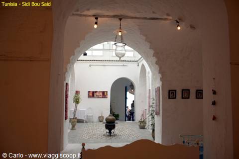 Whitewashed inner courtyard with arched doorways in Sidi Bou Said, hanging lamp and plant
