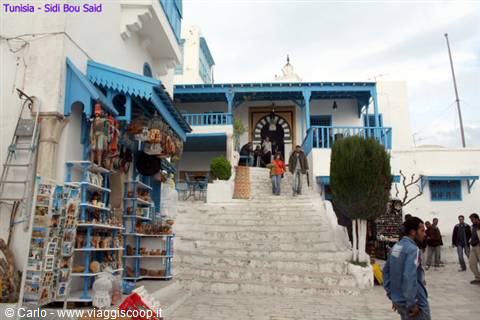 White staircase among whitewashed houses with blue doors, tourists and souvenir shop, Sidi Bou Said