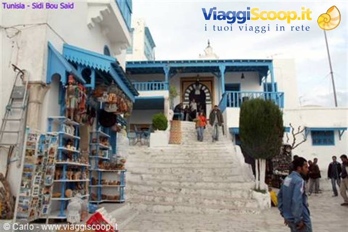 White staircase among whitewashed houses with blue doors, tourists and souvenir shop, Sidi Bou Said