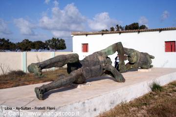 Bronze statue of falling Icarus before a white house in Favignana