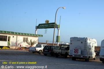 Camper van and pickup trucks parked at the Gheddafi entrance arch