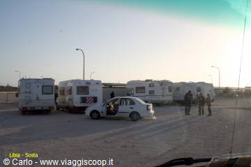 Caravans and cars parked on sand under hazy sky