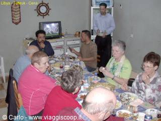 Tourists and Libyan guests dining together at a long set table