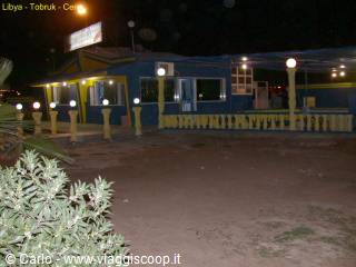 Lit-up restaurant at night in Tobruk, spherical lamp posts and sandy ground