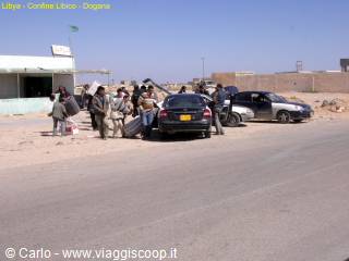 Travelers with luggage beside taxis at the Deqa desert border checkpoint