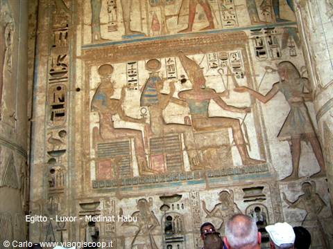 Tourists observe painted hieroglyphs on the columns of Medinat Habu temple in Luxor
