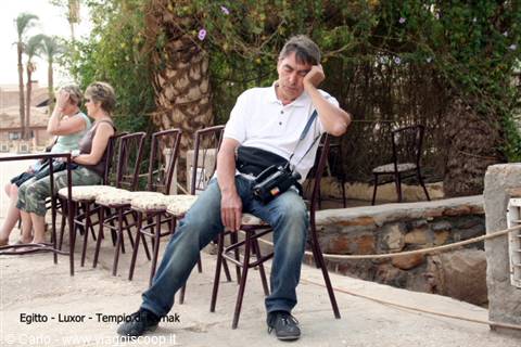 Tired tourist with camera sitting on an iron chair, Karnak Temple
