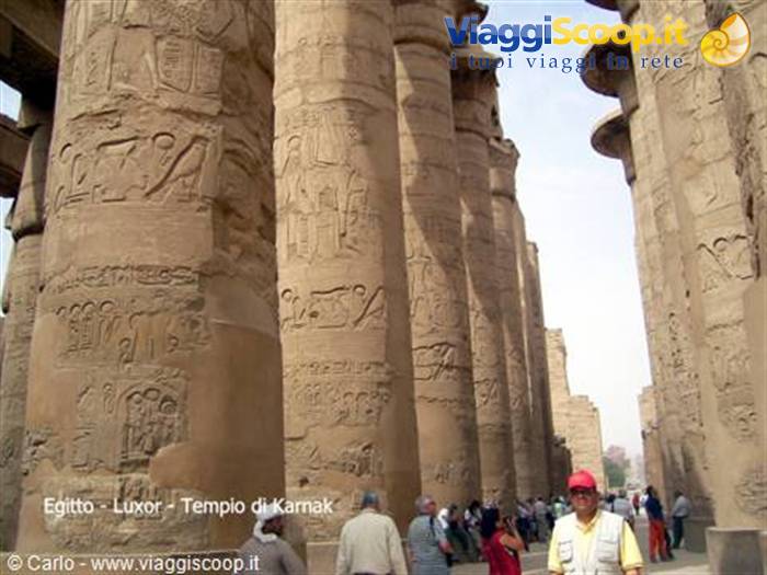 Tourists beneath giant hieroglyph-covered columns at Karnak Temple, Luxor