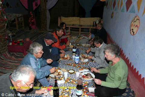Tourists eating dinner seated on the floor of a Bedouin camp tent
