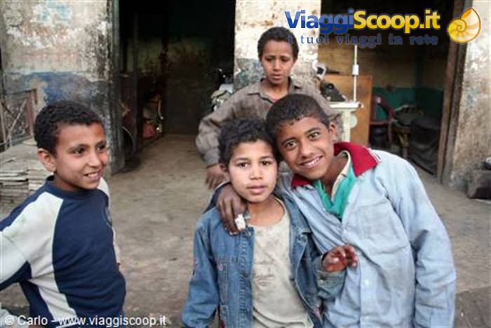 Four boys smiling together in front of a building, one in denim