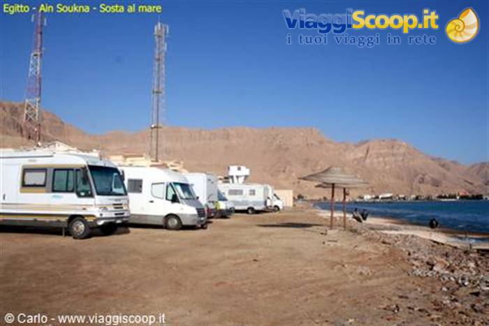 Motorhomes parked on red sand by the sea, desert mountains and antennas at Ain Soukhna
