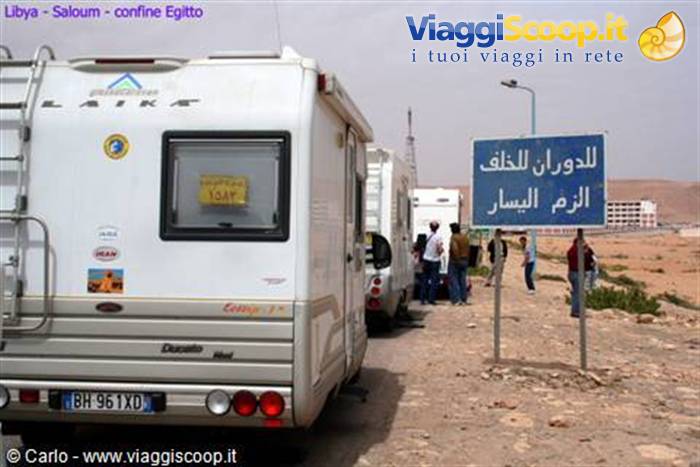 Campervans queuing at the Egypt border, bilingual road sign in the desert