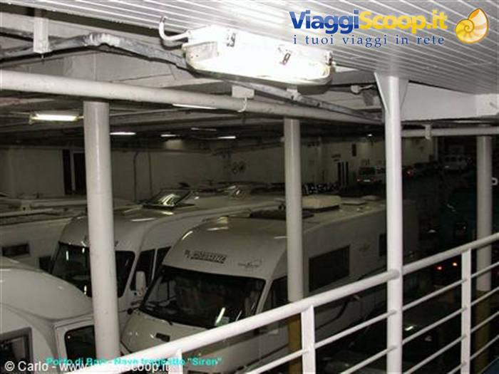 Motorhomes parked inside a ferry garage under fluorescent light