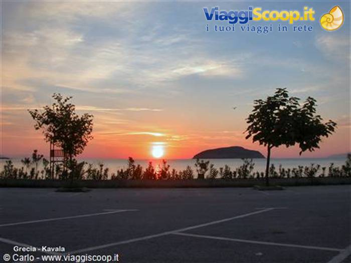 Sun rising over the sea in Kavala, trees and islet along the waterfront