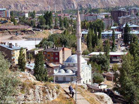 Mosque with minaret and grey dome among Divriği houses, daylight