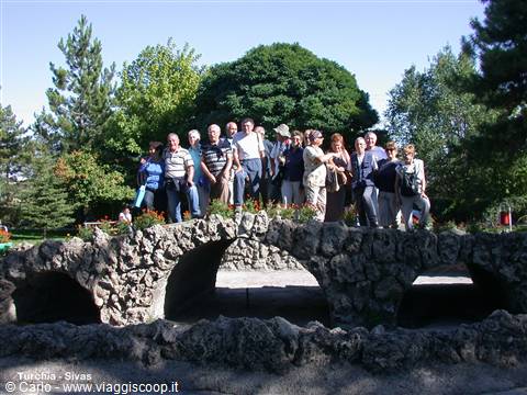 Tourist group on a stone arch bridge in a tree-filled park, Sivas