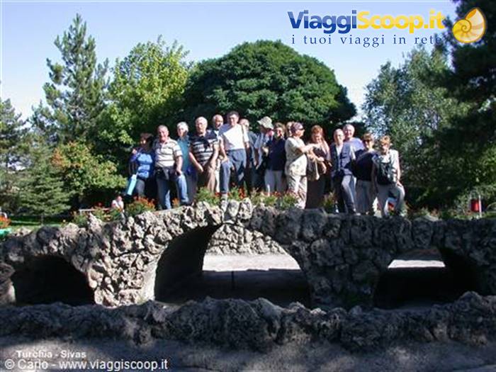 Tourist group on a stone arch bridge in a tree-filled park, Sivas