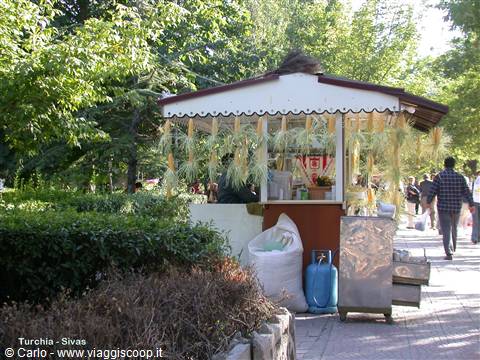 Corn kiosk in Sivas, cobs hanging from the roof, people walking by