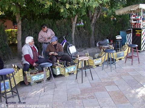 Shoeshine men working with stools and kits under trees in Sivas