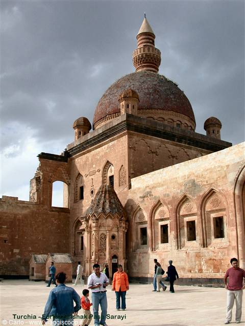 Tourists walk in the courtyard of Ishak Pasha Palace under dome and cloudy sky