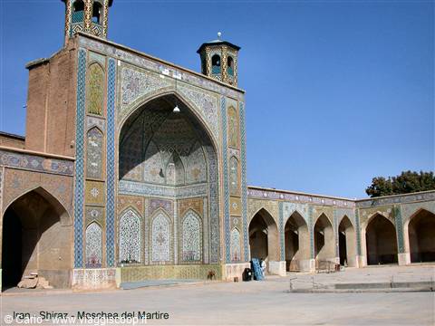 Mosque courtyard in Shiraz, tile-decorated iwan and arches under bright sun