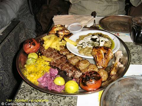 Metal platter with kebab, yellow rice, grilled tomatoes and chicken in Combad