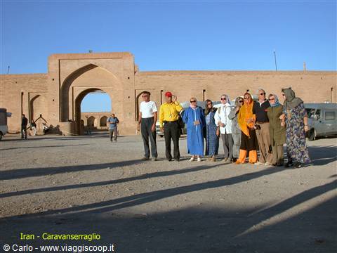 Tourists posing before the mud-brick gateway of Zein-o-din caravanserai