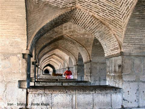 Brick vaults of Khaju Bridge in Isfahan, woman in red walks through arcade