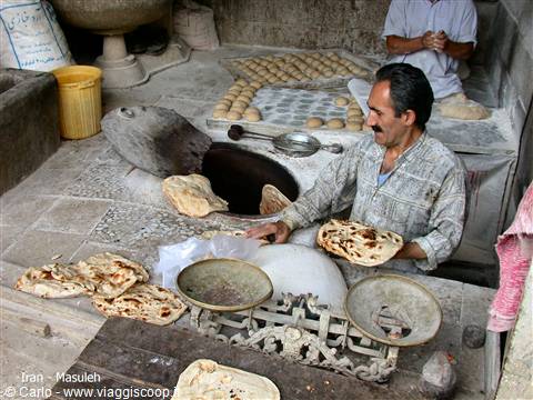 Baker in Masuleh baking traditional flatbread in a stone tandoor oven