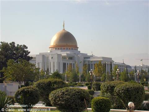 Presidential palace with golden dome in Ashgabat, manicured gardens under sunshine