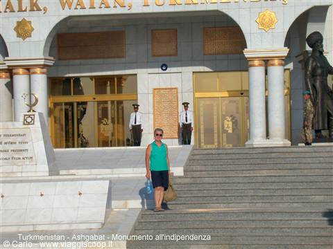Tourist at the entrance of Ashgabat Independence Monument, uniformed guards standing