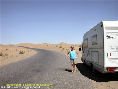 Woman beside a motorhome on the paved road through the Karakum desert, Turkmenistan