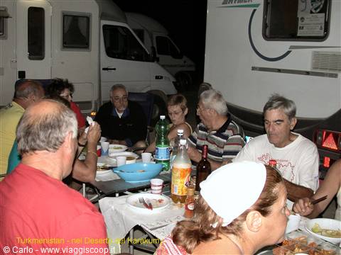 Campers having dinner together at night among campervans in the Karakum desert, Turkmenistan