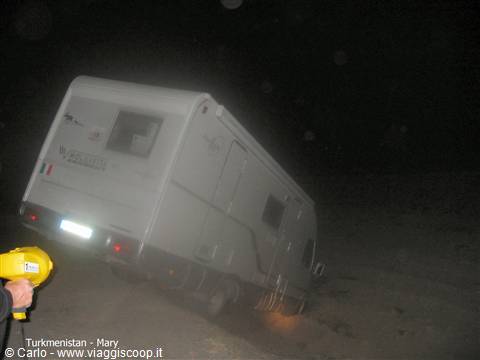 Motorhome tilted on sand at night in Mary, flashlight beam