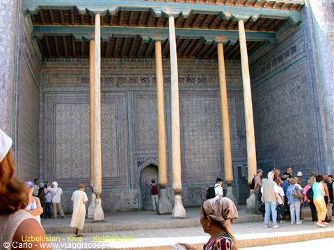 Tourists under the wooden columned portico of Khiva mosque
