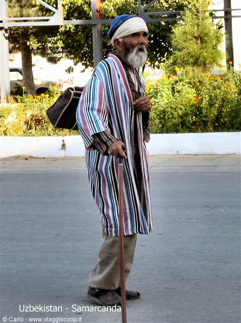 Elderly man in striped robe walking with cane on a Samarkand street