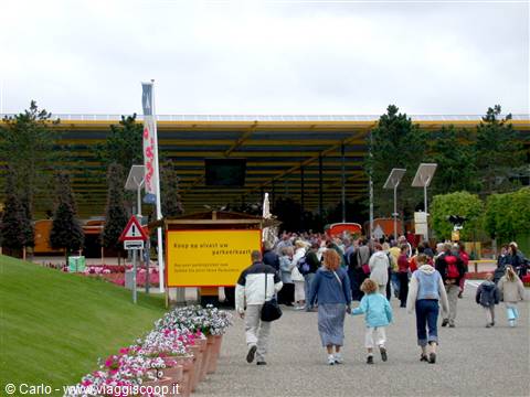 Visitors with children walk toward the large yellow Floriade pavilion