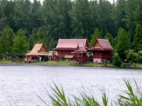 Wooden pavilions with red roofs by the lake, surrounded by green trees