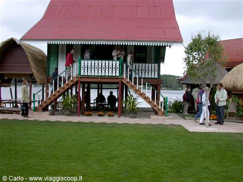 Traditional stilt house with red roof and staircase by the lake