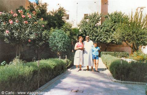 Tourists with a guide in a garden with oleanders and ochre walls