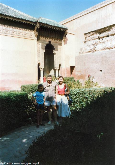 Family posing among hedges and pink walls by a carved stone archway