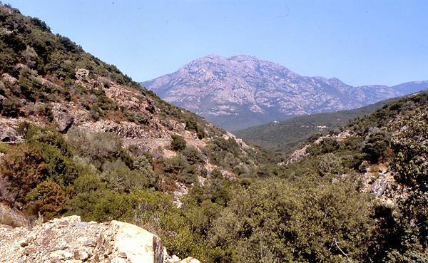 Granite mountain above a valley of Mediterranean shrubland, clear sky