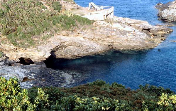 Limestone cliffs with sea cave, Mediterranean vegetation and concrete walkway