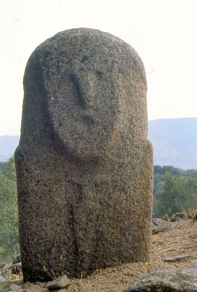 Granite statue-menhir with carved face at Filitosa, green hills behind