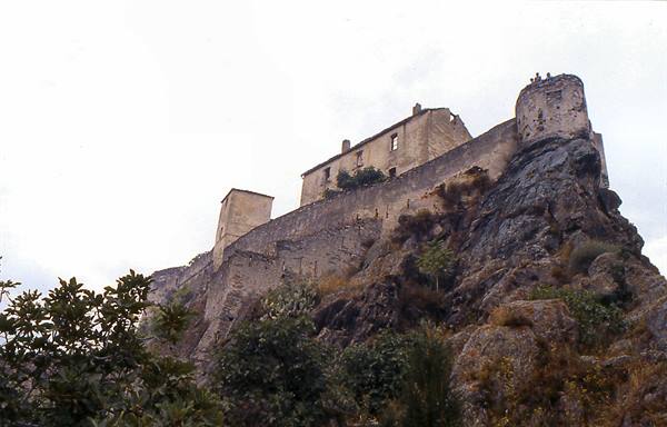 Old stone castle atop a rocky cliff under a gray sky
