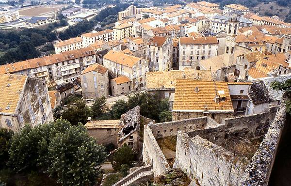 Town with terracotta roofs and stone houses seen from above, old ramparts in foreground