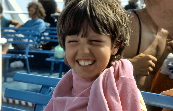 Smiling child wrapped in pink towel on ferry's blue seats